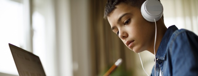 Teenage boy listening to music while doing homework